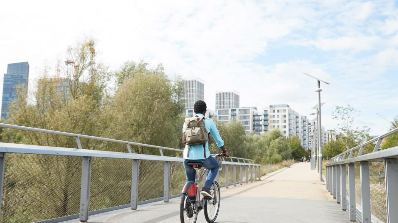 骑自行车的女孩在桥上驶向城市.